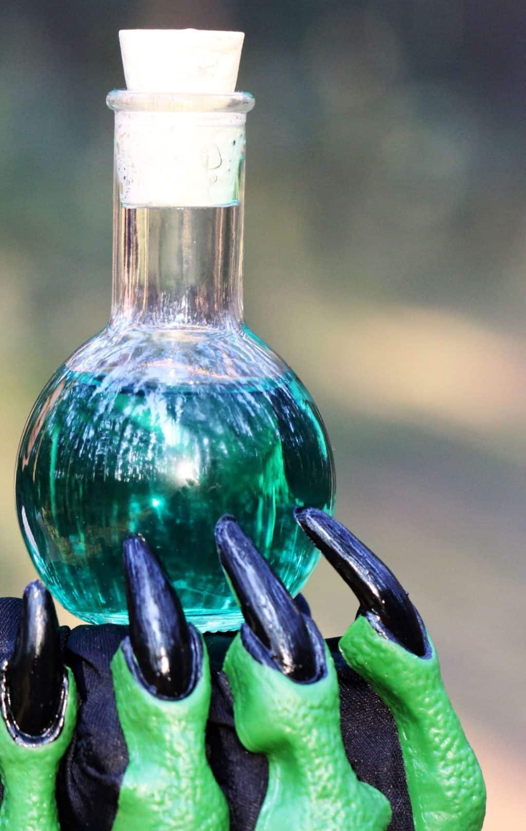 mano verde di strega che porge una pozione