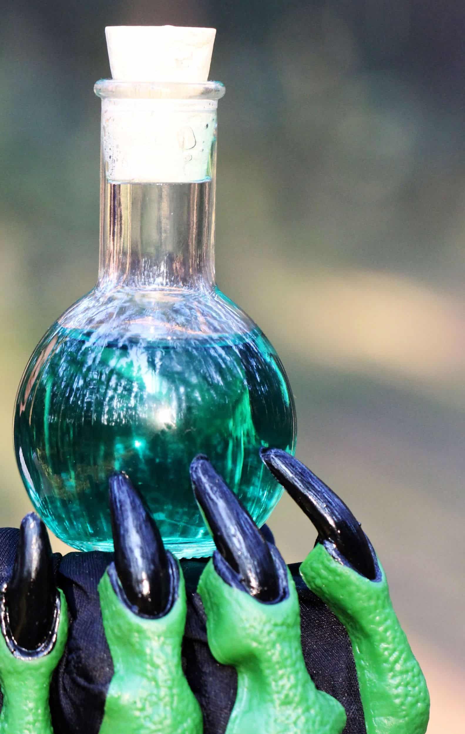 mano verde di strega che porge una pozione